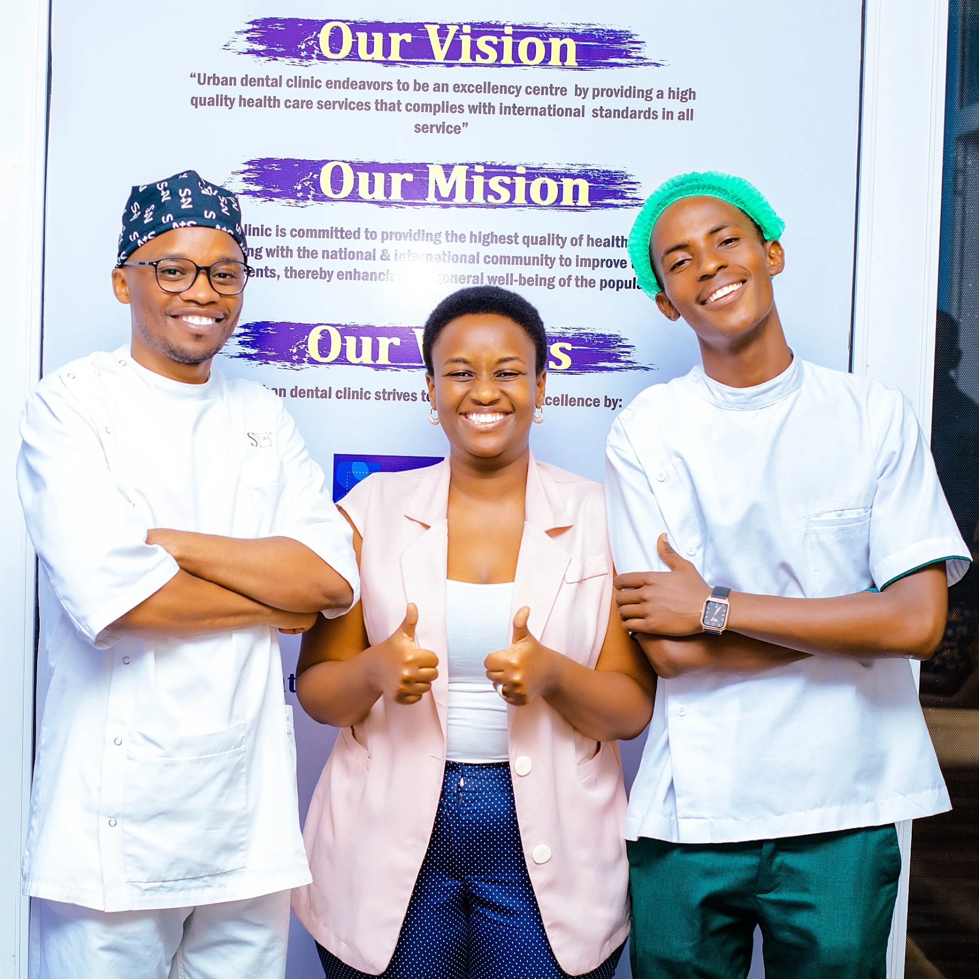Urban Dental Clinic team in front of the clinic vision and mission wall
